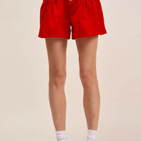 Red denim shorts with elastic waist, button front, and tied waist drawstring.