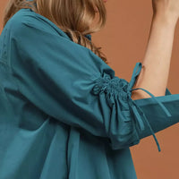 Teal dress sleeve close-up with gathered ruched cuff and button details