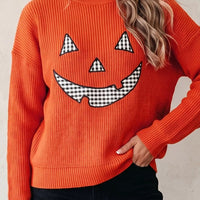 Orange knit sweater with jack-o-lantern face graphic and round crew neck