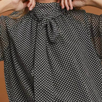 Black and white dot print tie-neck blouse with gathered neckline, front detail