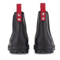 Rear view of black leather Chelsea boots with red pull tabs and lug soles.
