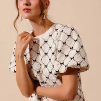 Ivory woven bubble sleeve top with black bow texture pattern, close side profile