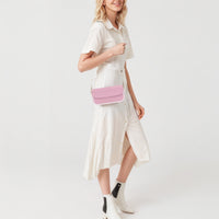 Pastel pink mini shoulder bag on a model, with flap front and chain strap