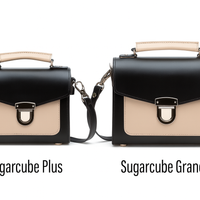 Pair of black leather crossbody handbags with beige flap and silver buckle, side-by-side