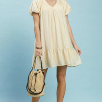 Cream mini shift dress with V-neck, puff sleeves, and ruffle hem, side view.
