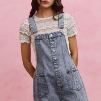 Light wash denim overall romper with adjustable straps and front buttons, chest pocket