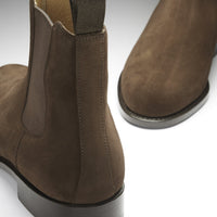 Brown suede Chelsea boot close-up showing the rear pull tab and heel