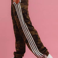 Camouflage track pants with bold white vertical side stripe and cuffed ankles.