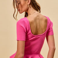Hot pink ribbed knit sweater top with peplum hem, shown from back