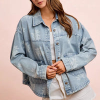 Light blue washed denim jacket with white floral print, button front, and flap chest pockets