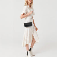 Black mini shoulder bag worn crossbody with gold chain strap and top flap