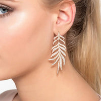 Silver feathered leaf drop earrings worn on a model's ear