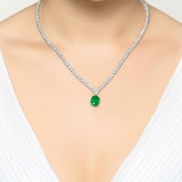 Silver tennis necklace with oval emerald pendant worn on a model