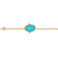 Gold chain bracelet close-up with blue opalite Hamsa charm and clear stones