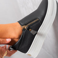 Black slip-on trainers with gold zipper pull and side zipper detail on white-trim sole