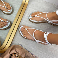 White faux leather lace-up T-strap sandals with ankle ties and studded flat sole