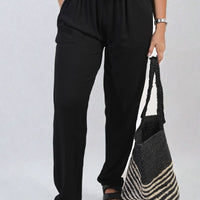 Black high-waist drawstring trousers with side pockets and gathered elastic waistband.