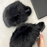 Black fuzzy open-back slippers with rounded toe and small logo patch