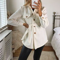 White belted jacket with flap pockets, gold buttons, and tie waist detail.