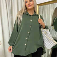 Oversized collared button-down top in dark green with gold buttons, roomy long sleeves.