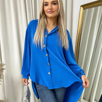 Oversized collared button-down top in bright royal blue with gold buttons and long sleeves.