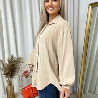 Oversized collared beige button-down top with long sleeves, button placket, curved hem