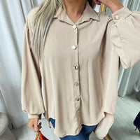 Oversized collared beige button-down shirt close-up with front buttons and soft puff sleeves