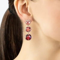 Rose gold earrings with pink, red, and dark red faceted stones in tiered drops