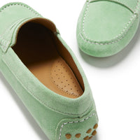 Green suede driving loafer close-up showing tan perforated insole and rubber heel studs.