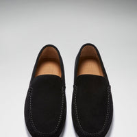 Pair of black suede driving loafers viewed from above, with tan leather lining and stitched trim.