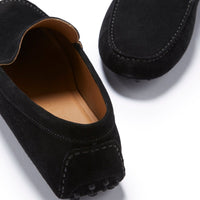 Black suede driving loafers showing the moc toe stitching, heel details, and tan lining.