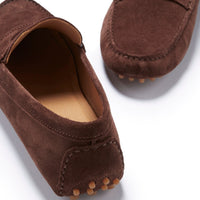 Brown suede driving loafers showing stitched heel panels and rubber sole pods