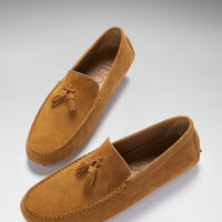 Pair of tan suede driving loafers with tassels and stitched moc toes, viewed at an angle