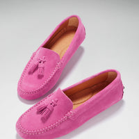 Pink suede tassel loafers shown at an angle, with stitched toes and tan lining.