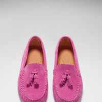 Pair of pink suede loafers with tassels, stitched apron toes, and tan insoles.