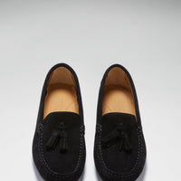 Pair of black suede tassel loafers viewed from above, showing tan insoles