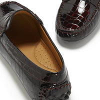 Patent leather loafer close-up showing croc-effect texture, stitched seams, and rubber heel nubs