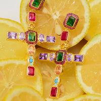 Gold cross gemstone earrings close-up with green red purple and blue stones