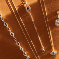 Gold-tone evil eye charm bracelets with blue oval stones and dangling eye pendants