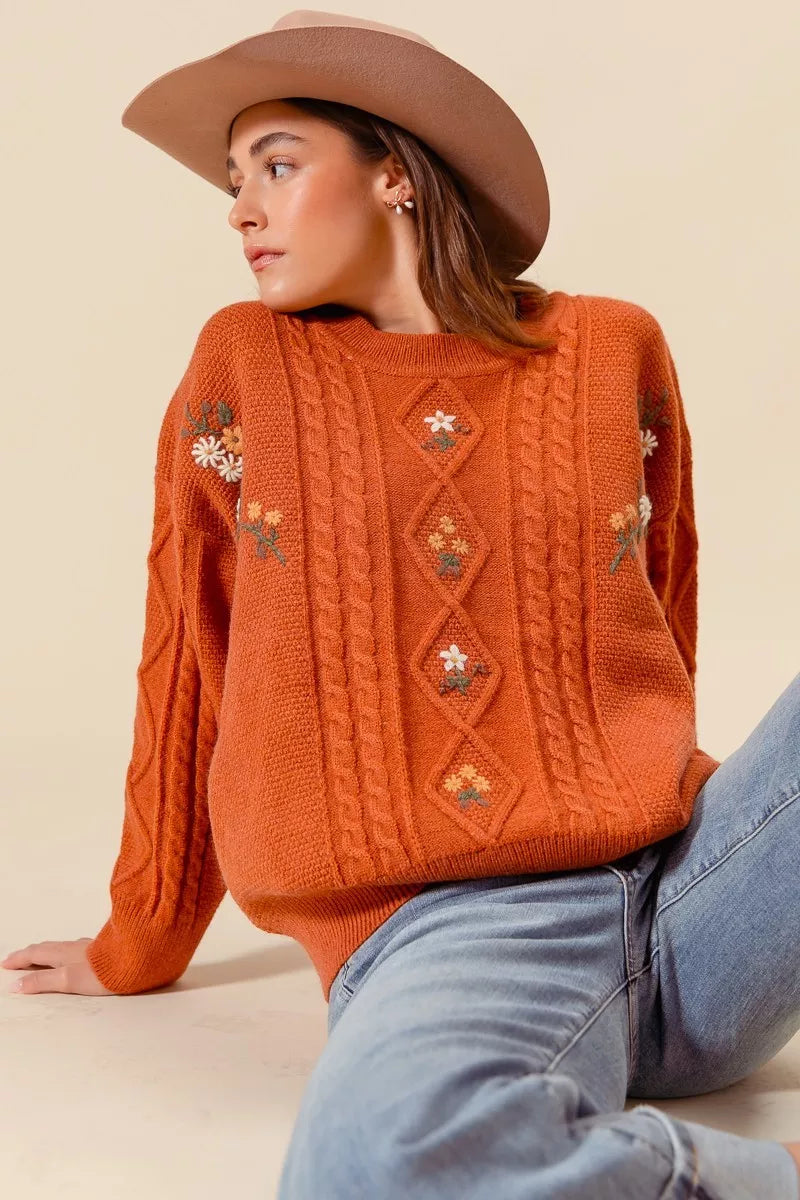 Brick cable-knit sweater with embroidered flower accents and diamond pattern panels