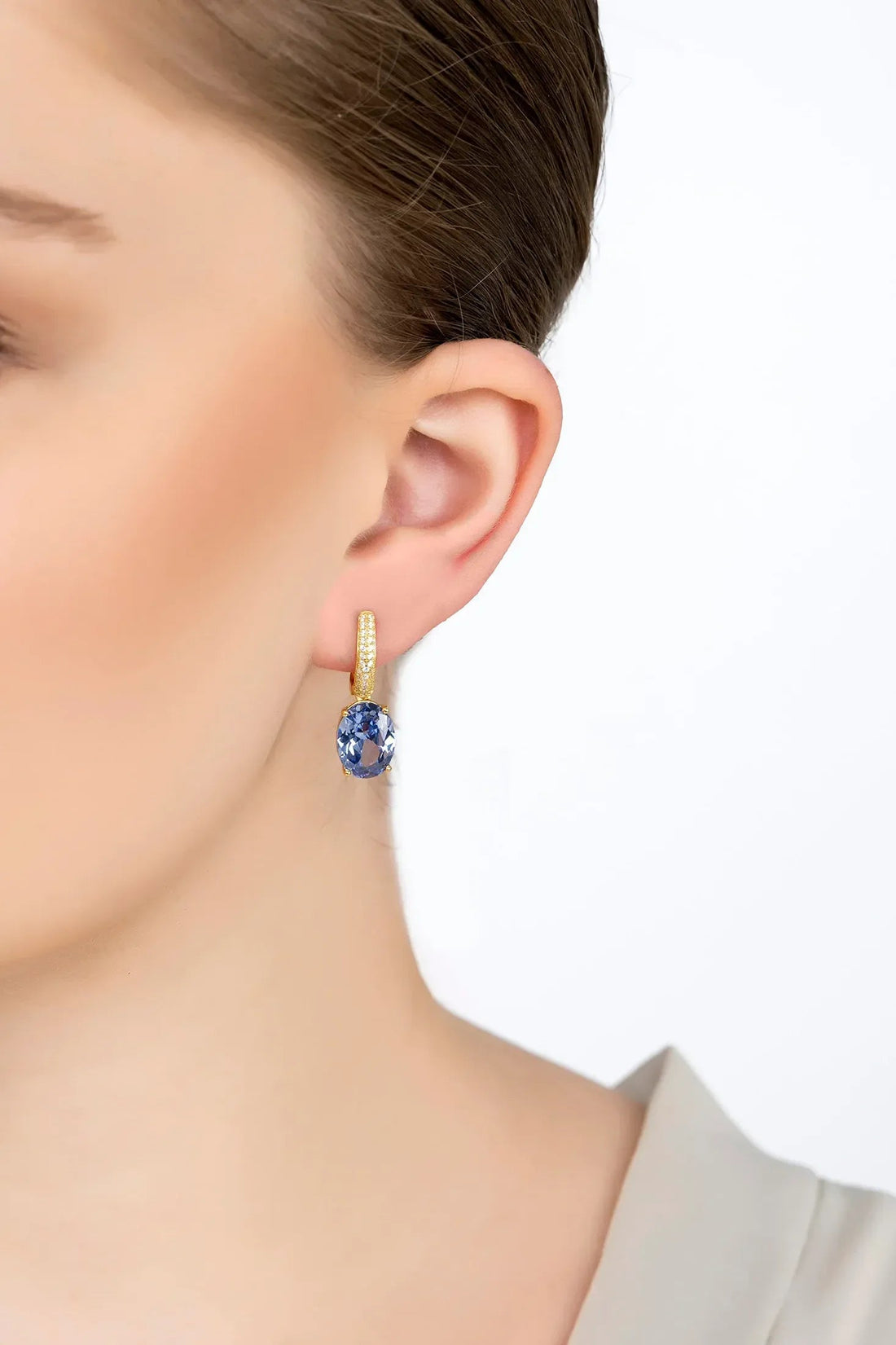 Alexandra gold oval drop earring with tanzanite stone, shown worn on ear