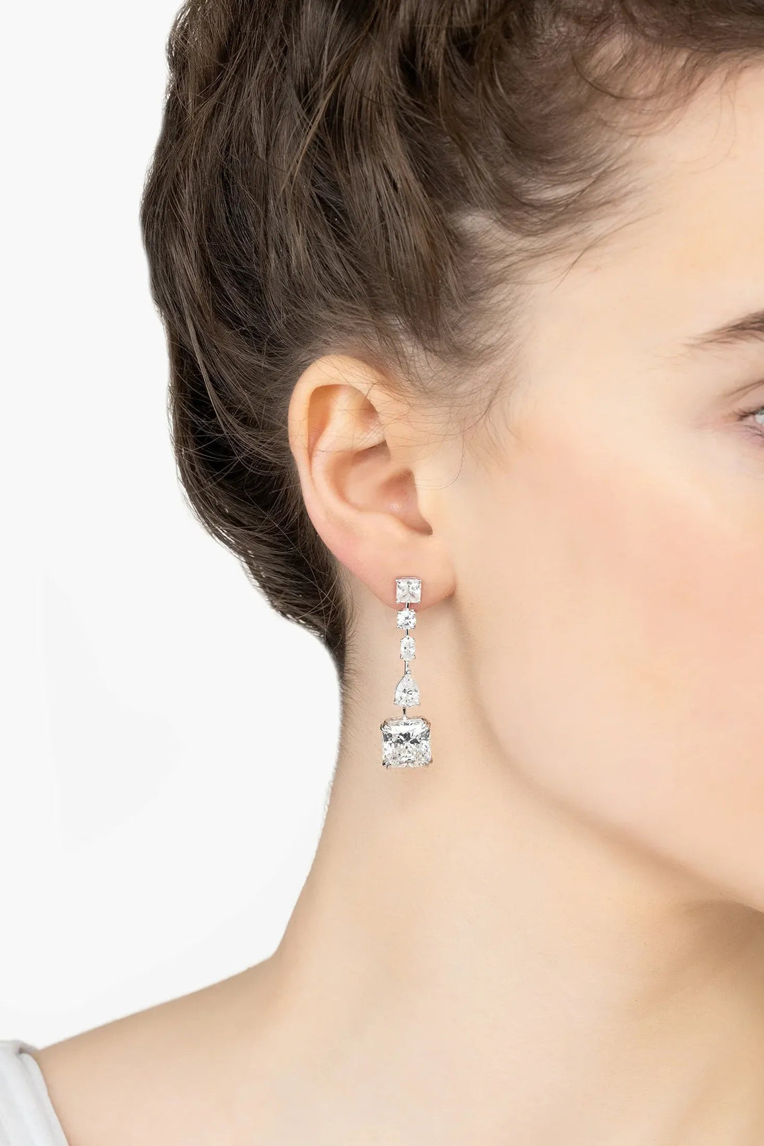 Silver moissanite drop earrings on ear, three stacked stones with a square centerpiece