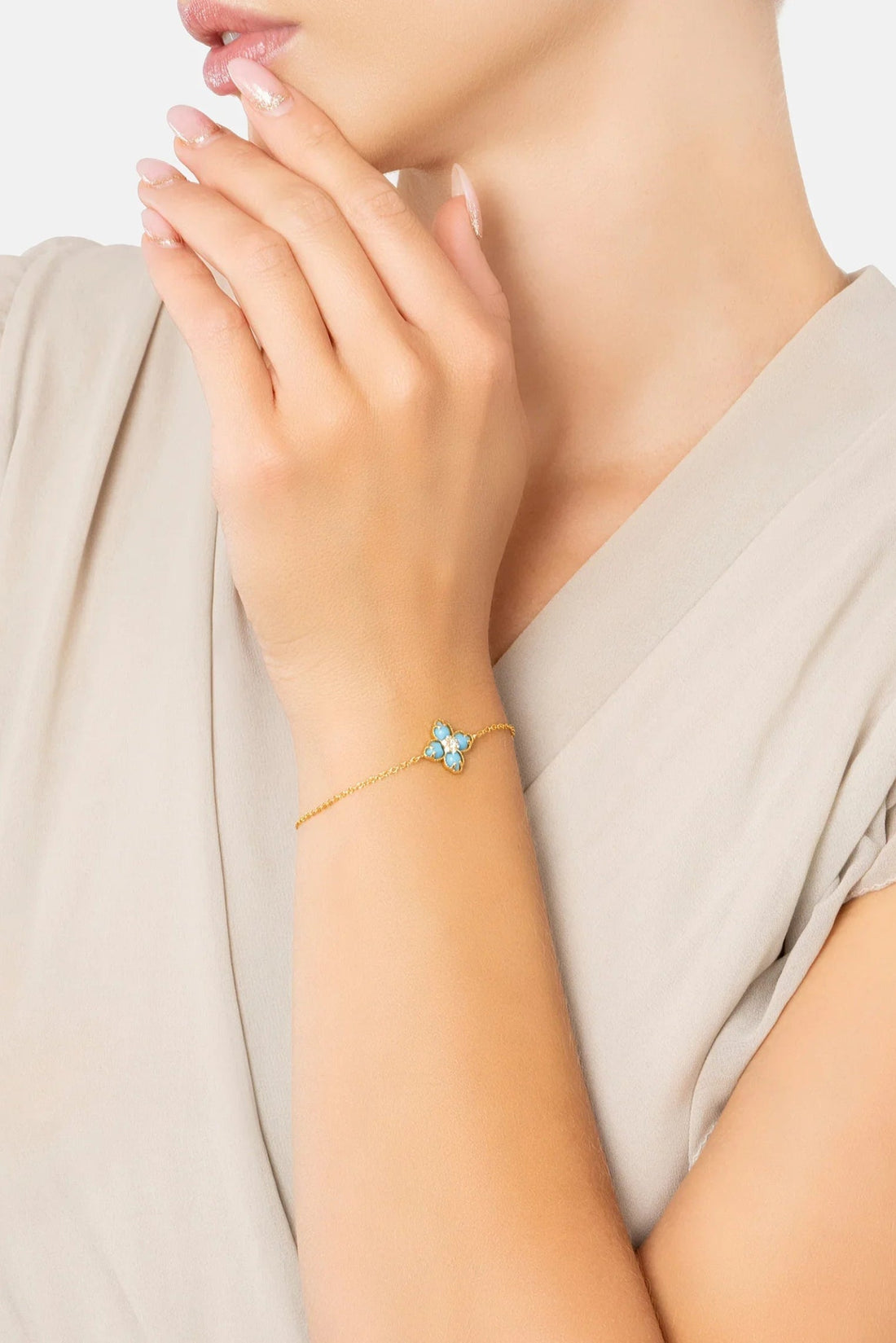 Gold-tone bracelet with blue clover charm and turquoise enamel on wrist
