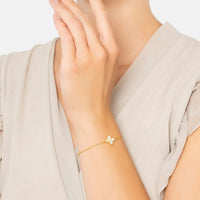 Gold bracelet with mother-of-pearl flower clover charm on wrist