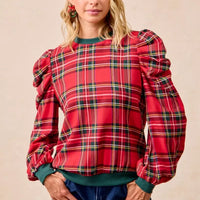 Red plaid puff-sleeve top with exaggerated shoulders and green ribbed cuffs