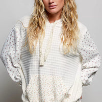 Cream knit hoodie with floral print sleeves, hood strings, and kangaroo pocket