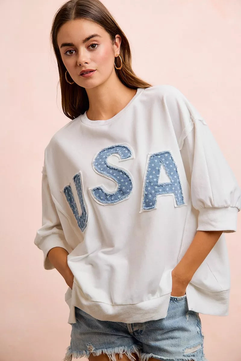 Ivory french terry sweatshirt with blue "USA" appliqued letters and loose elbow-length sleeves