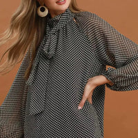 Black and white dot print tie-neck blouse with wide, draped sleeves