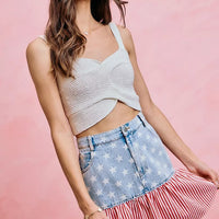 Denim mini skirt with star print panel and red-white striped ruffle hem, side view