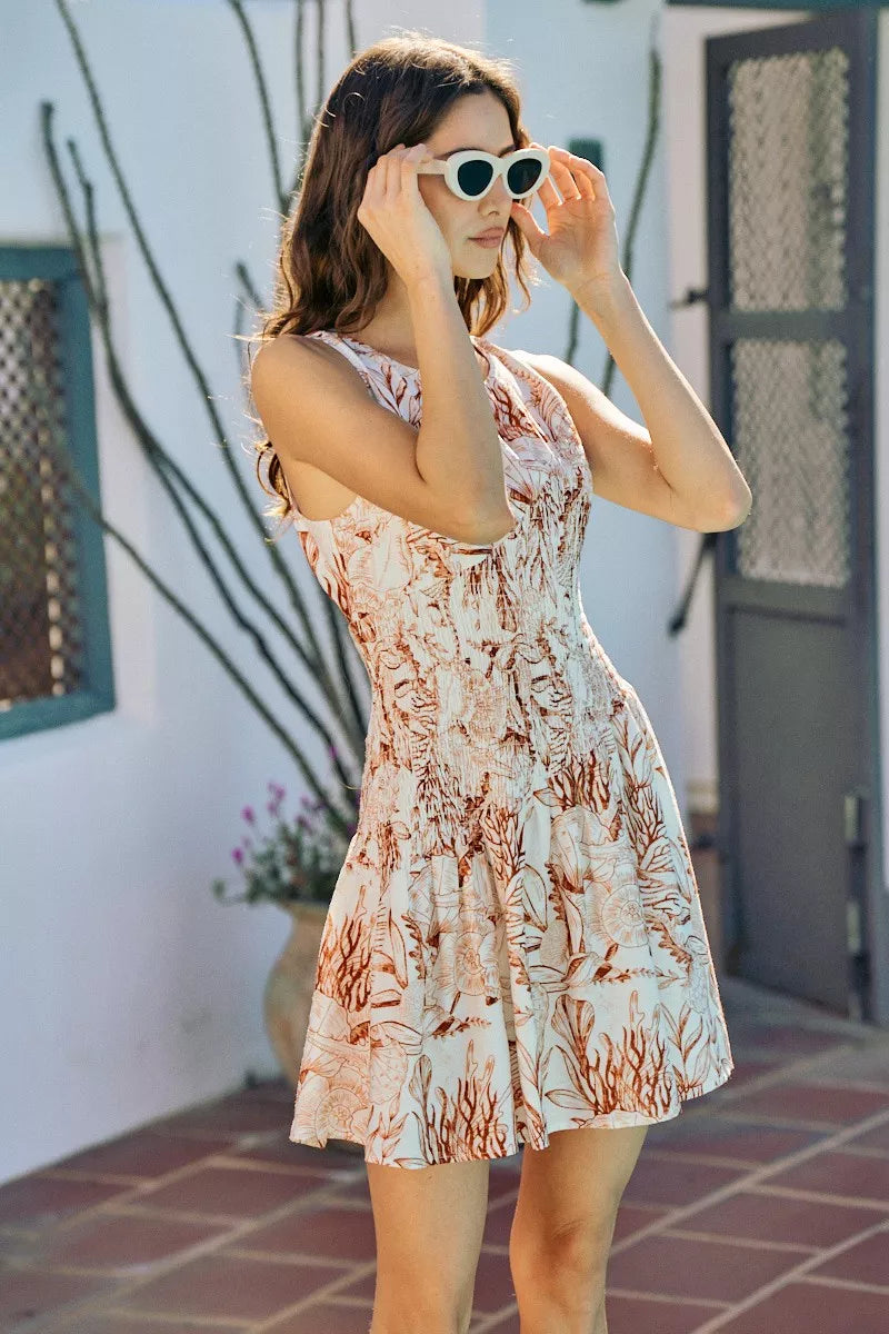 Smocked fit-and-flare mini dress in coral and white shell print, sleeveless and lined